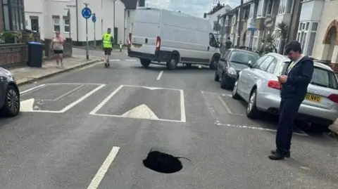 We are Northampton Residential street with houses visible and a hole to the right of the centre line