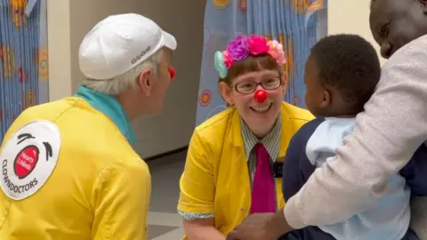 Two clown doctors talking to a toddler