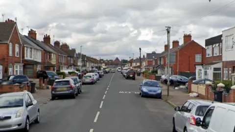 A residential street with parked cars on either side