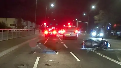 A car following a motorcyclist in the dark before crashing into him