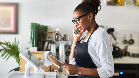 Waitress taking order on phone at restaurant and writing on notepad