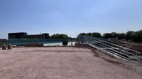 National Highways An image of a new bridge, with trees and a building in the background.