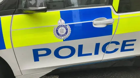 BBC A close-up of a police car showing the word 'police' in large letters along the side. 
