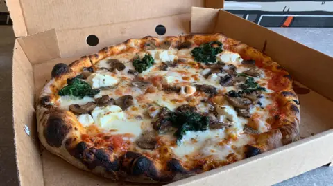 A mushroom and mascarpone pizza in a cardboard takeaway box