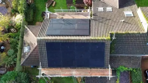 An aerial shot of the roof of a house fitted with solar panels.