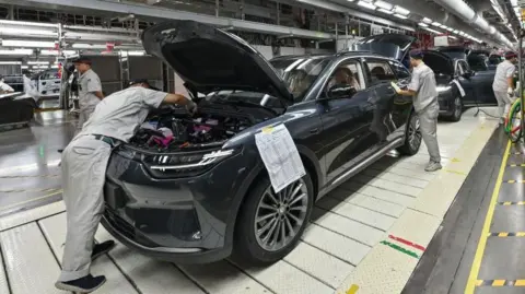 Getty Images Employees work on an electric vehicle production line at a factory in Jinhua, China