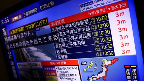 Reuters A television screen shows a news report on Japan Weather Agency's tsunami warning.