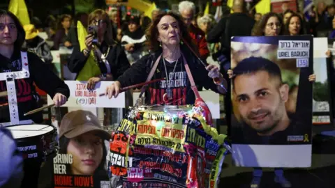 Reuters A woman beats a drum as she marched with others who hold flags and placards bearing the faces of hostages