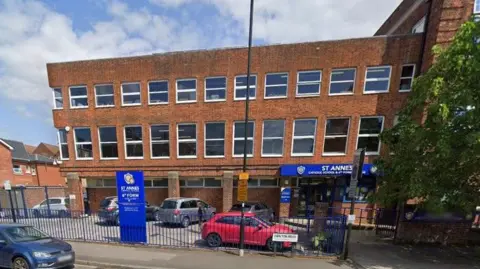 Google Street View of St Anne's school - a late 20th century brick building with three storeys and a flat roof with large sash windows along the two upper floors.