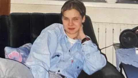 An old photograph of Izabela sat down wearing a blue denim jacket
