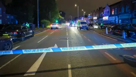 AshleyStocksMedia Police tape covers Dickenson Road in Longsight on Monday evening.