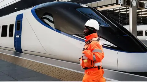 EPA/Shuttershock A HS2 worker walks past a HS2 advertisement board