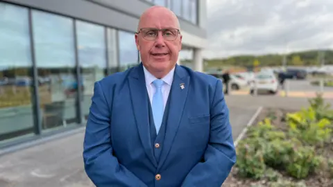 A man wearing a blue suit and blue tie
