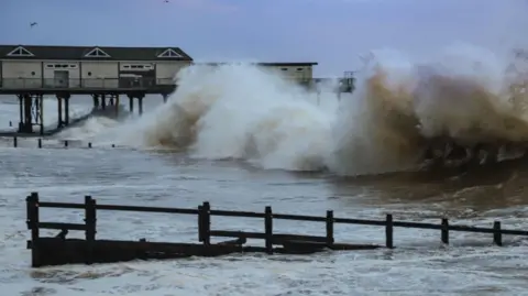 A wave crashes into a pier in Teignmouth