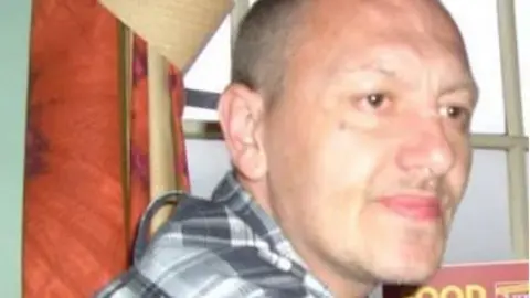 Garry Claydon. A man with short, grey hair wearing a grey and white checked shirt.