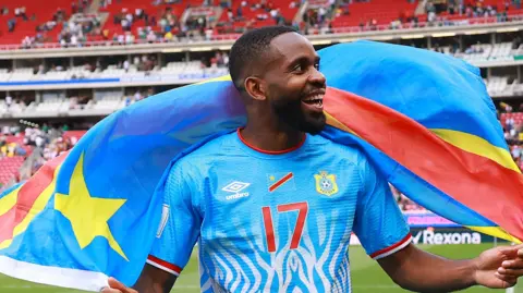 Cédric Bakambu celebrates on the pitch with DR Congo's national flag