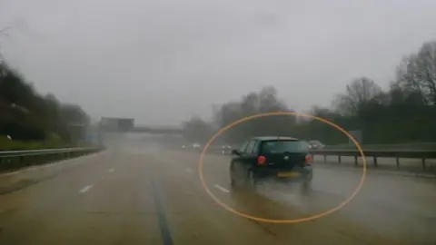 Dash cam footage showing a black polo in the fast lane of the M27 in wet weather.