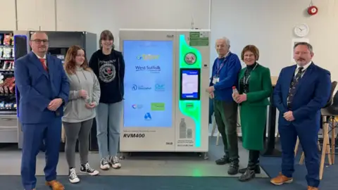 Councillors and other people standing either side of a reverse vending machine in West Suffolk. 