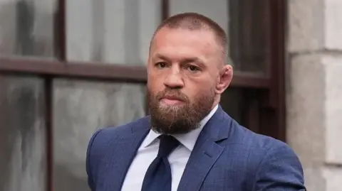 Niall Carson/PA Wire Conor McGregor leaving the High Court in Dublin on 5 November.   He has a full beard and is wearing a blue suit, navy tie and a white shirt.