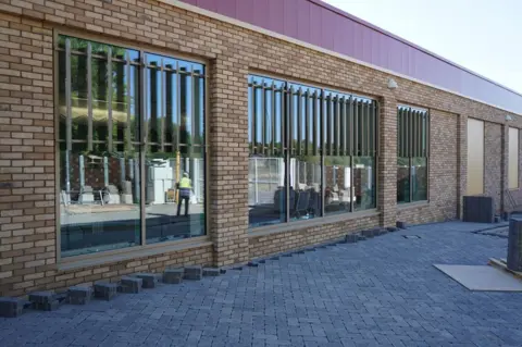 Wychavon The outside of leisure centre which has large windows which has the reflection of a worker in it. 