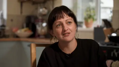 Parent Celeste Lewis sitting in a kitchen