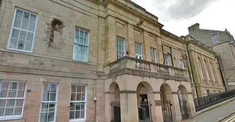 Google A stone court building with an arched entrance