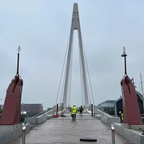 Two red pillars turned lamp posts standing in front of the Govan-Partick Bridge