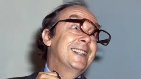 BBC Eric Morecambe, mengenakan dasi kupu-kupu, tertawa dan kacamata miring, 12/07/1979.