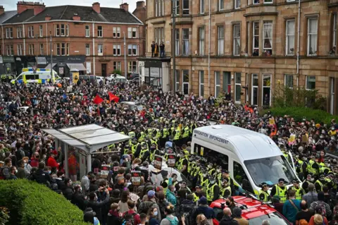 Getty Images Hundreds of protestors surround a immigration enforcement van in the southside of Glasgow as they wait for police to escort two men detained by the Home Office