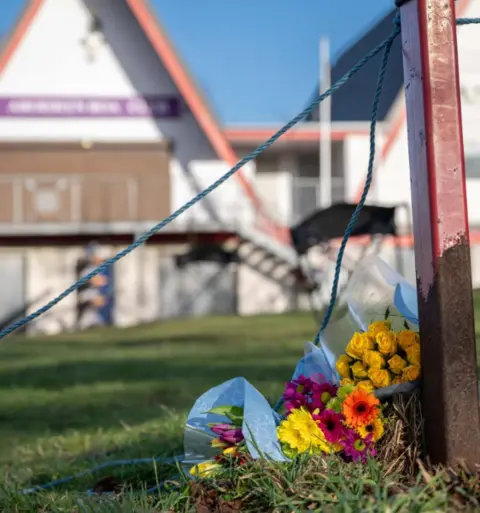 PA Media Three bunches of of flowers have been placed on the grass outside Aberdeen boat club