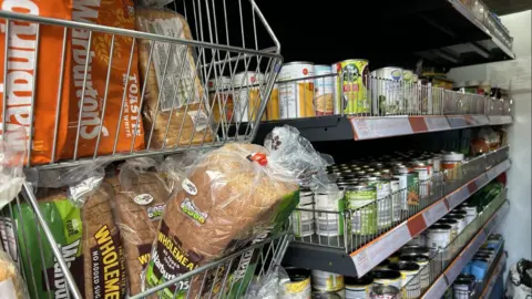 General view of shelves filled with bread and tinned goods