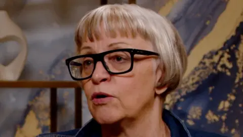 Philippa Perry has light short hair and is wearing black glasses.