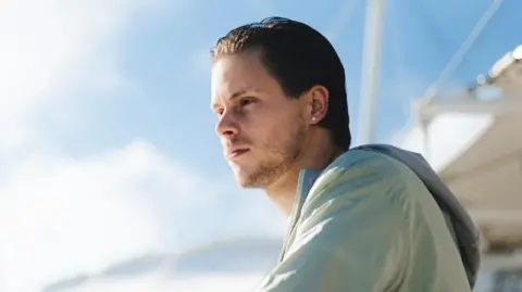 A man leaning on a white fence 