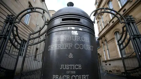 Getty Images The black gates at the entrance of Edinburgh Sheriff Court. In the centre is a large bollard which has white print reading "Edinburgh Sheriff Court and Justice of the Peace Court".