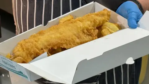 Kevin Shoesmith/BBC An open box displays a battered fish on top of chips