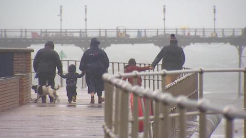 A family on a rainy and windy pier