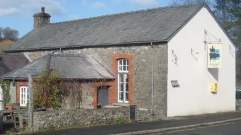 Rose Geraedts The outside of the Welsh Rarebit Centre. It is an old renovated school and on the right is a sign saying the Welsh Rarebit Centre. The picture has been taken on a sunny day.