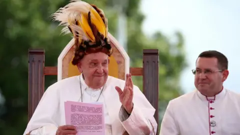 Pope Francis wears traditional headwear during his visit to Vanimo