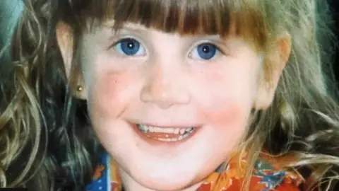 Pacemaker Shows a young girl with blue eyes, fair hair and an earring in her right ear smiling