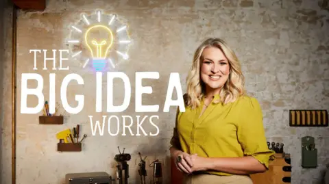 Sara Davies stands in front of a workbench full of tools. She is wearing a yellow blouse. The words "The Big Idea Works" are displayed next to her. The local includes a lightbulb above the "I" in idea.