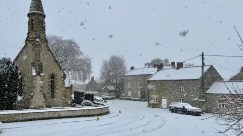 Philippa A picturesque snow-covered village. To the left of the picture is a church, while to the right are cottages.