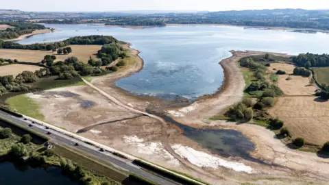 PA Media Aerial shot of a half empty lake. You can see very little water towards the edge of the lake and old roads and a bridge that are usually underwater.