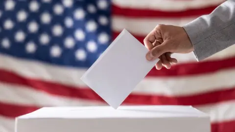 A hand puts a ballot in a ballot box