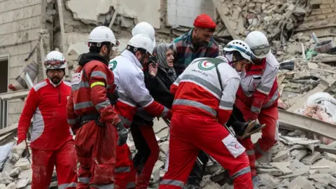 Rescuers carry an elderly woman following a strike on a residential building in Tehran, Iran. Photo: 16 March 2026