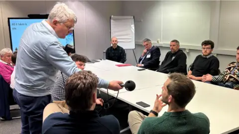 Football players from Saints Old Boys Football club sitting around a white table in the BBC