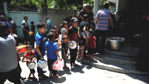 Palestinians in northern Gaza queue  in front of 