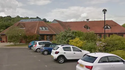 Google A red brick building with cars in the front of it.
