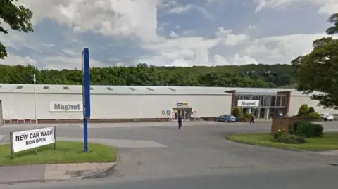 LDRS An image showing a Magnet kitchen showroom in a building on the side of a road. It is a large warehouse style building with what look like corrugated iron sides.