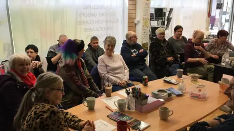 Anxious Minds A group of people gathered around a table in conversation