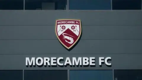 Morecambe's logo at their Mazuma Stadium home